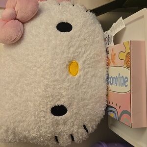 This is a white Hello Kitty sherpa-like decorative pillow with a pink bow